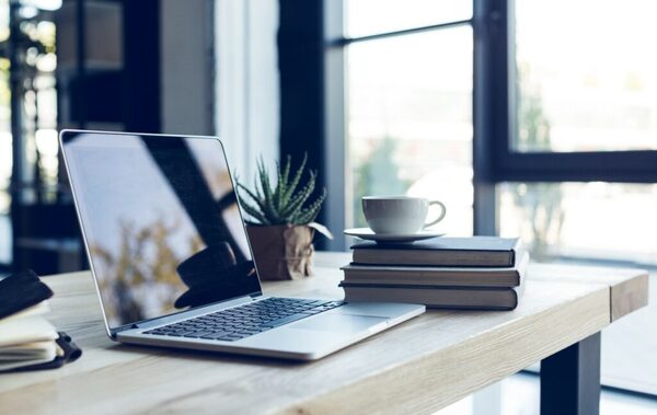 Minimal desk with laptop, glasses, and notebook — tidy workspace